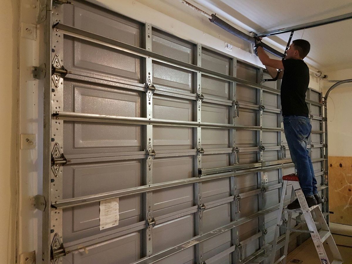 Technician replacing torsion springs on garage door in Broward County